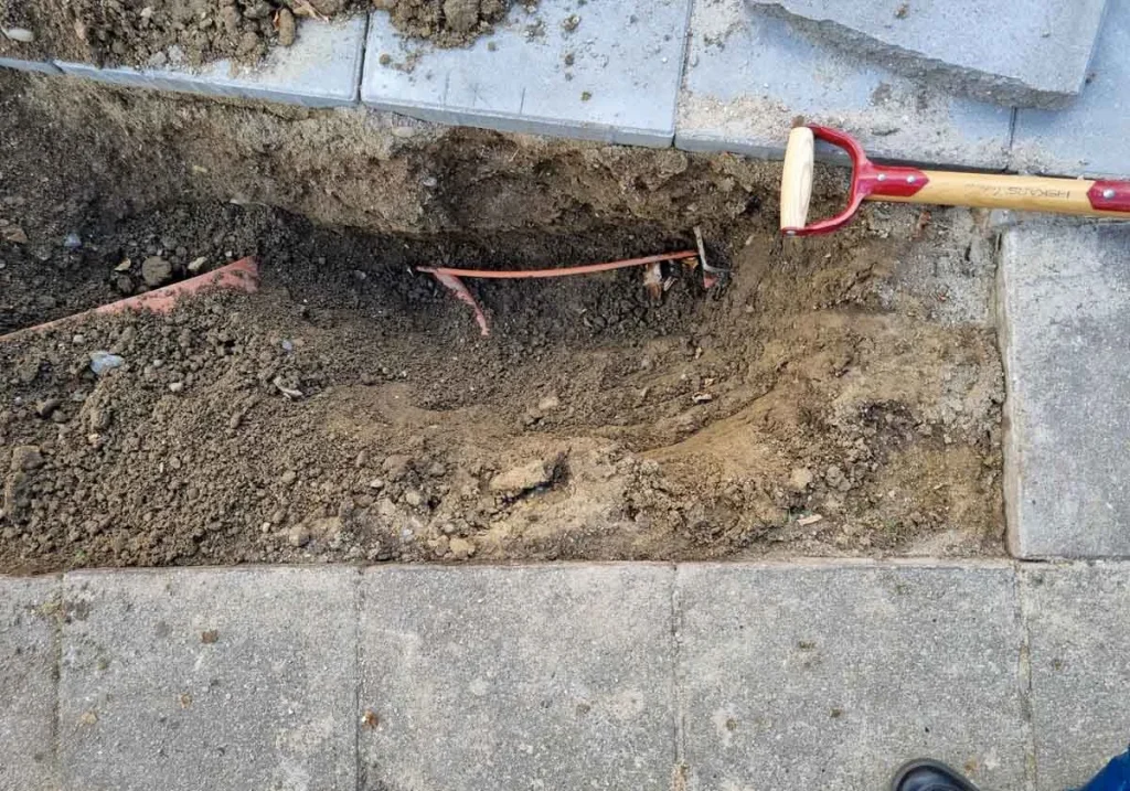 Fibernet kabler i jorden ved siden af fortorv og nyt område med fliser