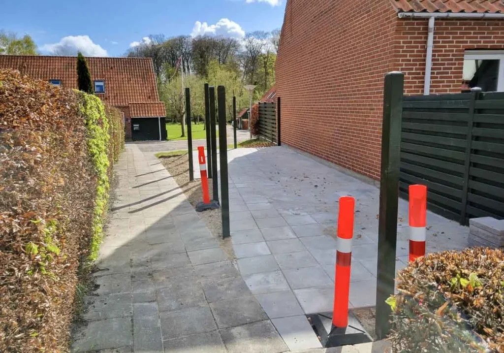 Området ved gavlen til nr. 15 er belagt med flliser og stolper til hegn er sat op 26. april 2023