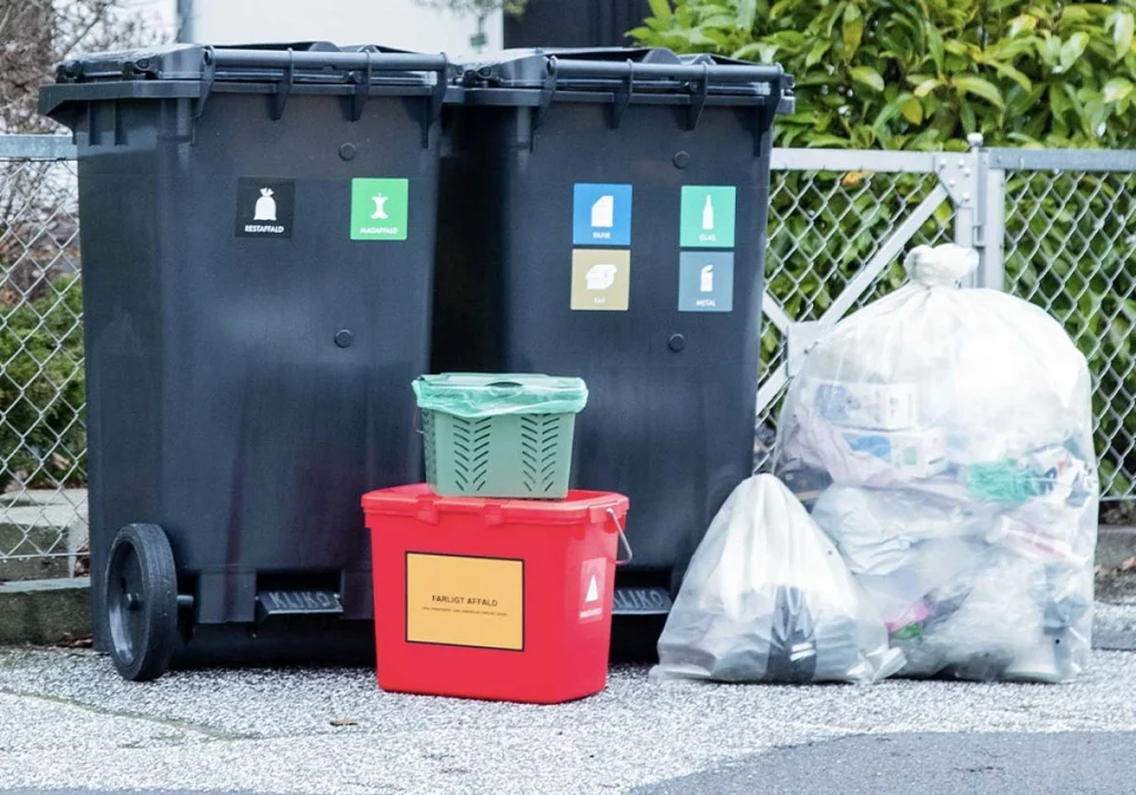 Forskellige affaldsbeholdere og plastiksække med karton og plast