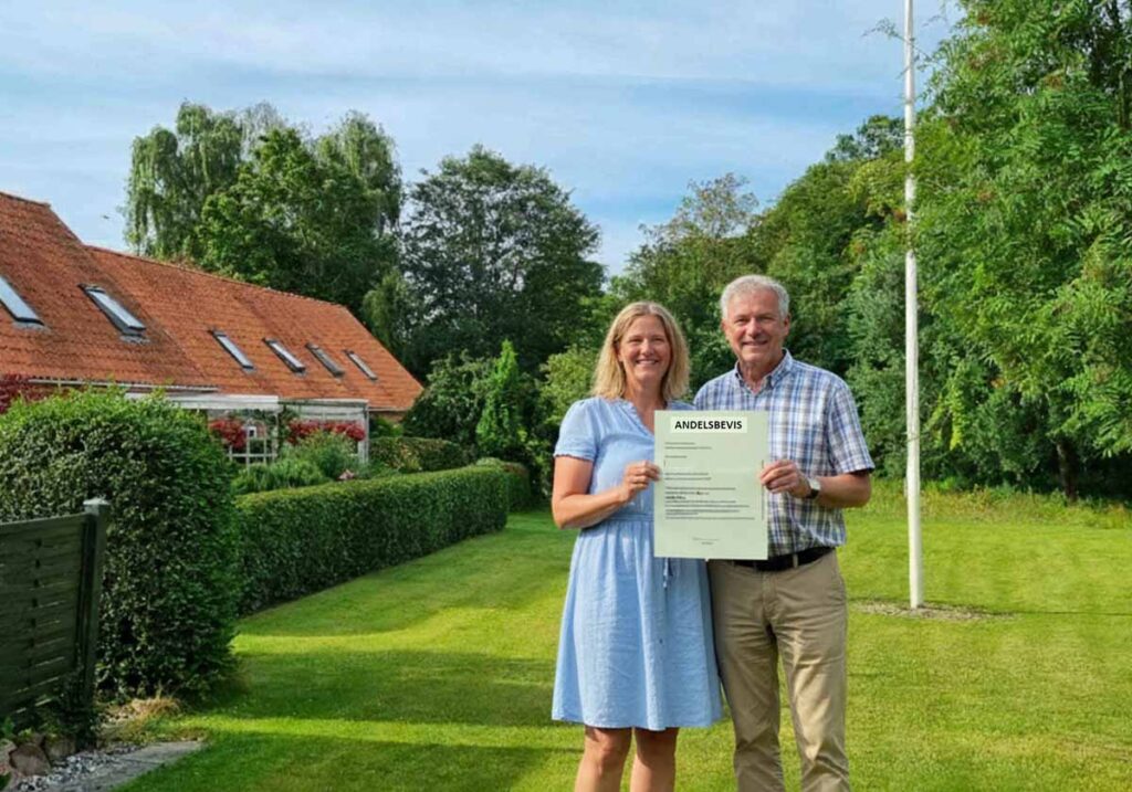 Ægtepar viser Andelsbevis på græsplænen
